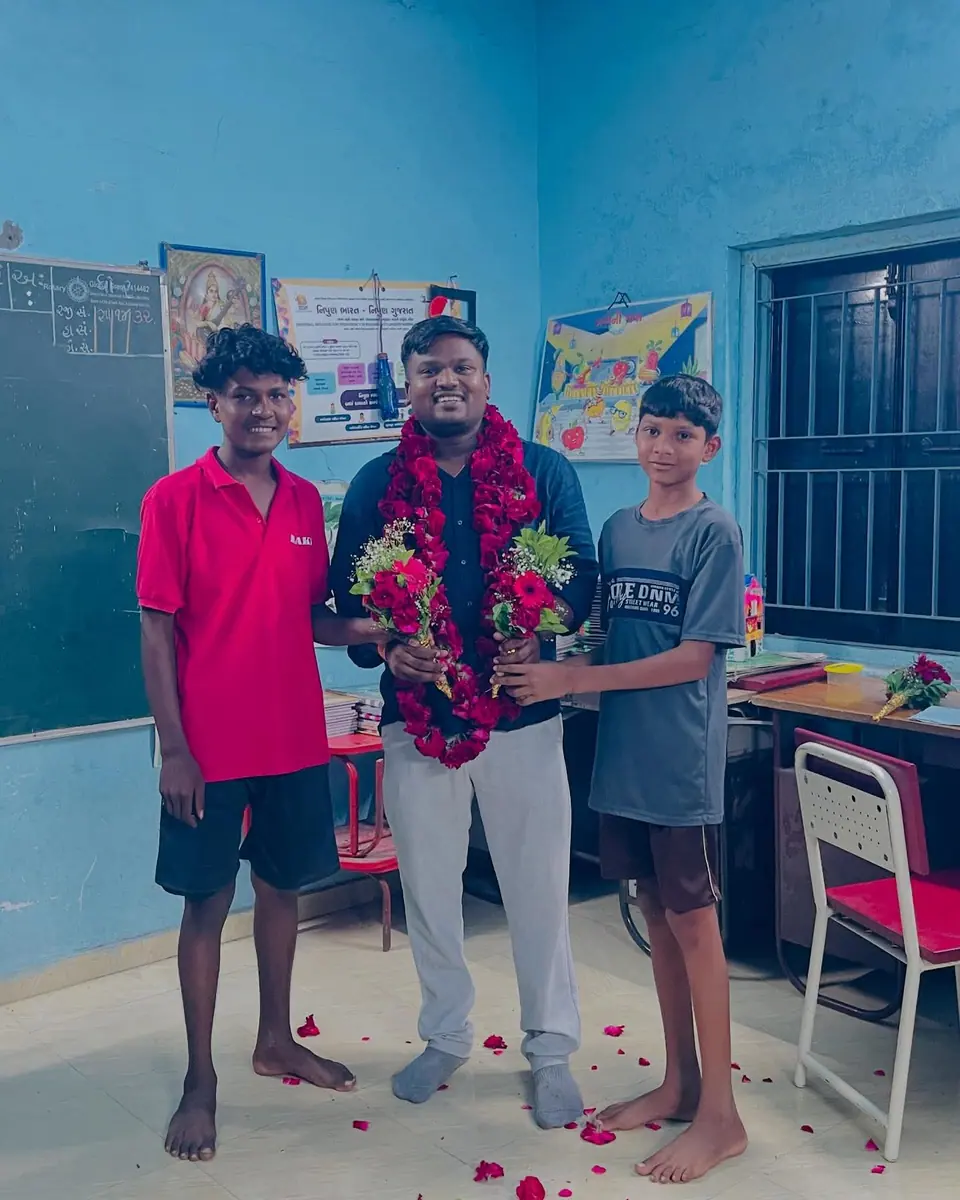 Man garlanded in classroom with two boys