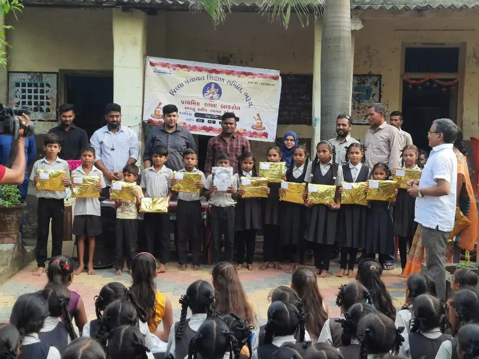 Schoolchildren holding gift packets in front of banner