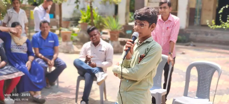 Boy speaking with mic, guests seated